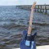 Blue Flame maple-topped tele on a stand by the water