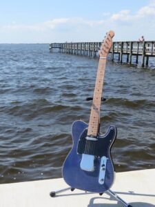 Blue Flame maple-topped tele on a stand by the water